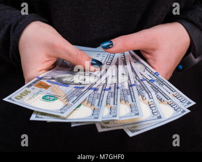 Donna con mano di dollari isolati su sfondo nero. Ragazza conteggiare denaro. Foto Stock