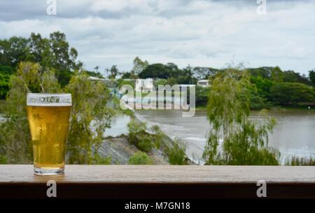 Bere una birra con vedute di acqua traboccante il weir dopo i recenti heavy rain, Riverview Tavern di Douglas Townsville Queensland Australia Foto Stock