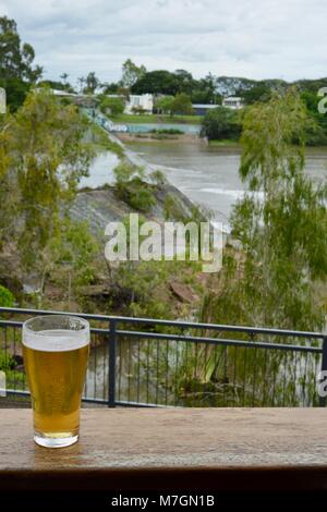 Bere una birra con vedute di acqua traboccante il weir dopo i recenti heavy rain, Riverview Tavern di Douglas Townsville Queensland Australia Foto Stock