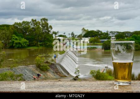 Bere una birra con vedute di acqua traboccante il weir dopo i recenti heavy rain, Riverview Tavern di Douglas Townsville Queensland Australia Foto Stock