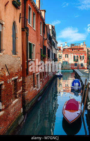 Barche in stretto canale lungo vecchie case di mattoni a Venezia, Italia ( composizione verticale). Foto Stock