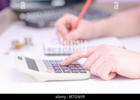 Foto di una mano conta su di una calcolatrice e tenendo una matita rossa. Close up di un uomo conta su una calcolatrice. I dati finanziari analizing. Foto Stock