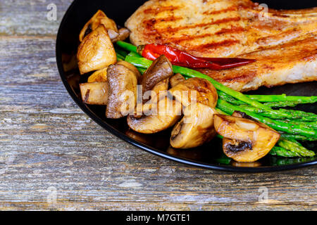 Bistecca di carne di maiale con verdure asparagi e funghi Foto Stock