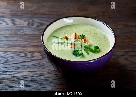 Inverno Vegaterian split pea curcuma zuppa decorate con crostini e verde in ceramica di colore viola ciotola di legno scuro di sfondo, vista dall'alto, close-up. T Foto Stock
