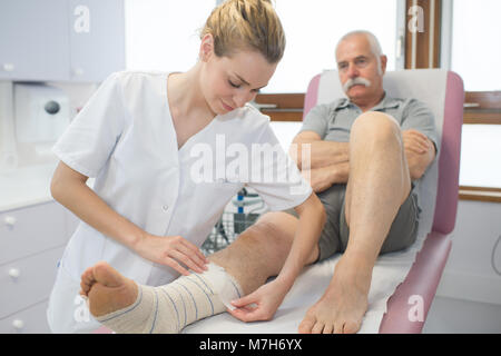 Fissatore infermiere cast sulla gamba del paziente in ospedale Foto Stock