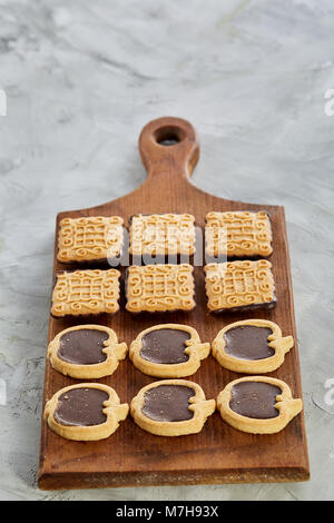 Vista superiore ritratto di close-up di piazza gustosi biscotti al cioccolato e a forma di apple di cookie sul brown tagliere di legno su una trama backgr astratto Foto Stock