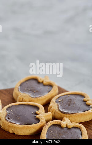 Vista superiore ritratto di close-up di gustosa apple al cioccolato a forma di cookie sul brown tagliere di legno su una texture di sfondo astratto, profondità minima Foto Stock