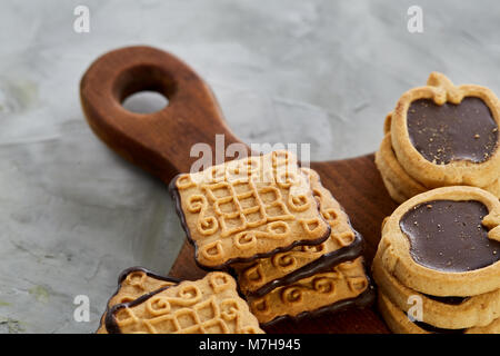 Vista superiore ritratto di close-up di piazza gustosi biscotti al cioccolato e a forma di apple di cookie sul brown tagliere di legno su una trama backgr astratto Foto Stock