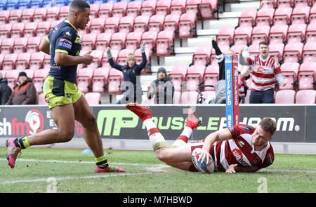 Il Wigan Warriors Joe Burgess passa per una prova passato Wakefield Trinità di Reece Lyne (sinistra) durante la Betfred Super League match al DW Stadium, Wigan. Foto Stock