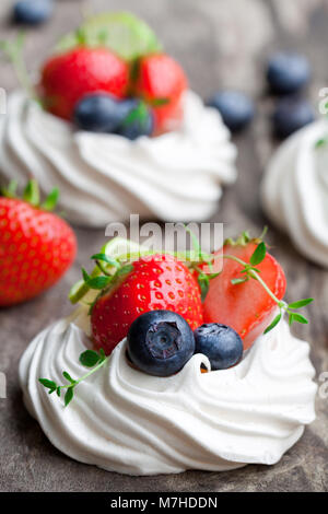 Mini Pavlova meringa torte con le bacche e le lime sul rustico sfondo di legno Foto Stock