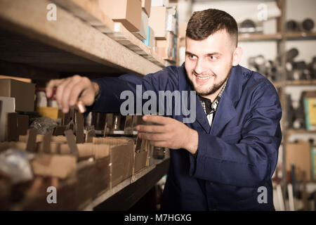 Attraente uomo lavoratore ordinamento ingegneria sanitaria dettagli in officina Foto Stock