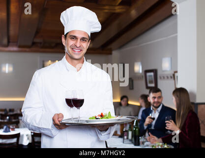 Ritratto di bello chef maschio con vassoio accogliente ristorante Foto Stock
