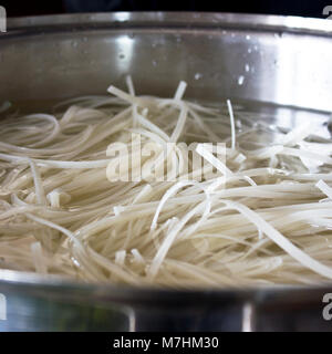 Riso tagliatelle in grande pentola in acciaio. Cucina asiatica. Foto Stock