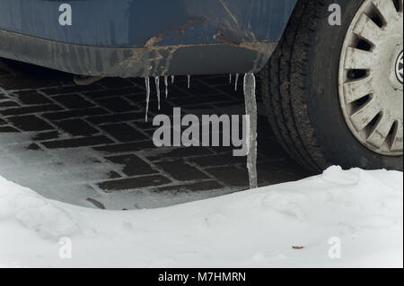 La nevicata rivestito di auto e furgoni dove la neve di fusione è il congelamento con grandi ghiaccioli dal rivestimento della massa di giunzione auto bloccata e congelata Foto Stock