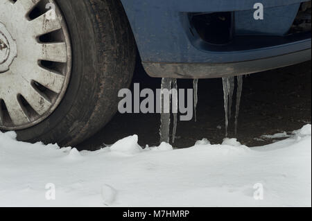 La nevicata rivestito di auto e furgoni dove la neve di fusione è il congelamento con grandi ghiaccioli dal rivestimento della massa di giunzione auto bloccata e congelata Foto Stock