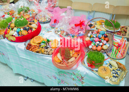 Novruz in Azerbaigian. Uova colorate per Pasqua e dolci tradizionali su sfondo bianco. Messa a fuoco selettiva. Piastra con dolci nazionali per pasticceria Novruz celebrazione Foto Stock