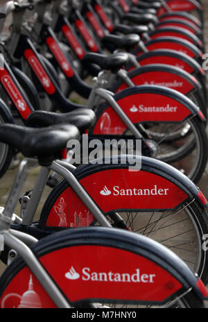 Marca Santander le biciclette a noleggio sono assicurate in rack sul lato nord del fiume Tamigi, di Westminster a Londra il 11 marzo 2018. Foto Stock