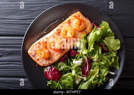 Cibo delizioso: salmone al forno con gamberi in salsa di miele e insalata fresca su una piastra di close-up su una tavola orizzontale di vista in pianta da sopra Foto Stock