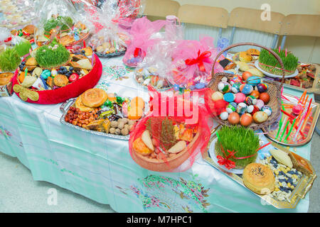 Novruz in Azerbaigian. Uova colorate per Pasqua e dolci tradizionali su sfondo bianco. Messa a fuoco selettiva. Piastra con dolci nazionali per pasticceria Novruz celebrazione Foto Stock