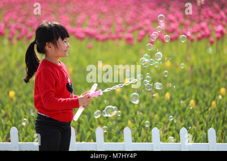 Taizhou, cinese della Provincia di Zhejiang. Decimo Mar, 2018. Un bambino gioca tra tulip presso un parco nella città di Wenling, est della Cina di Provincia dello Zhejiang, 10 marzo 2018. I residenti locali trascorrere il weekend all'aperto per godere il paesaggio della molla quando la temperatura aumenta. Credito: Zhou Xuejun/Xinhua/Alamy Live News Foto Stock