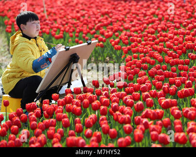 Taizhou, cinese della Provincia di Zhejiang. Decimo Mar, 2018. Un bambino di pitture tra tulip presso un parco nella città di Wenling, est della Cina di Provincia dello Zhejiang, 10 marzo 2018. I residenti locali trascorrere il weekend all'aperto per godere il paesaggio della molla quando la temperatura aumenta. Credito: Zhou Xuejun/Xinhua/Alamy Live News Foto Stock