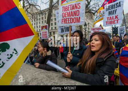 Londra, Regno Unito. Il 10 marzo 2018. Persone tengono cartelli e bandiere del rally prima dell'annuale Tibet libertà marzo a Londra per commemorare il 59e anniversario della Rivolta Nazionale Tibetana. Diverse centinaia di persone, compresi molti tibetani e i sostenitori di raccogliere a Downing St prima di marciare a una protesta presso l'ambasciata cinese. Prima del mese di marzo a sinistra vi era un minuto di silenzio per coloro che sono morti, compresi da auto-immolazione, e una lunga preghiera tibetano, seguita dal canto del popolo tibetano inno nazionale. Credito: ZUMA Press, Inc./Alamy Live News Foto Stock