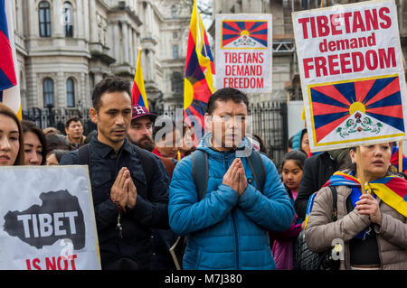 Londra, Regno Unito. Il 10 marzo 2018. Persone che pregano al rally prima dell'annuale Tibet libertà marzo a Londra per commemorare il 59e anniversario della Rivolta Nazionale Tibetana. Diverse centinaia di persone, compresi molti tibetani e i sostenitori di raccogliere a Downing St prima di marciare a una protesta presso l'ambasciata cinese. Prima del mese di marzo a sinistra vi era un minuto di silenzio per coloro che sono morti, compresi da auto-immolazione, e una lunga preghiera tibetano, seguita dal canto del popolo tibetano inno nazionale. Credito: ZUMA Press, Inc./Alamy Live News Foto Stock