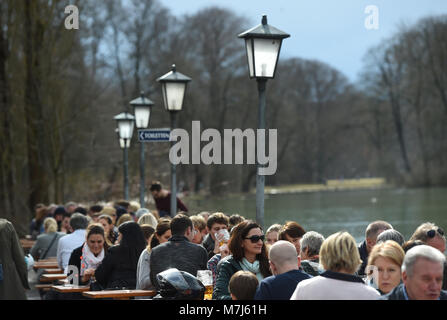 11 marzo 2018, Germania, Monaco di Baviera: Gente seduta al sole in un giardino della birra al Seehaus am Kleinhesseloher Vedi nell'Englischer Garten . Foto: Andreas Gebert/dpa Foto Stock