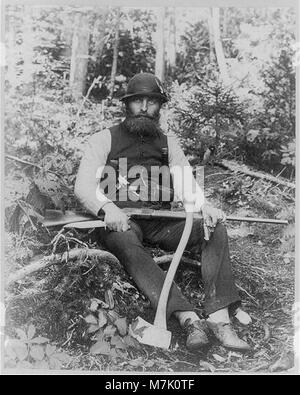 Questa fotografia raffigura un uomo barbuto del Maine, armato di varie armi tra cui un'ascia, un fucile, un coltello da caccia e due pistole. L'immagine ritrae una figura aspra probabilmente della fine del XIX o dell'inizio del XX secolo. Foto Stock