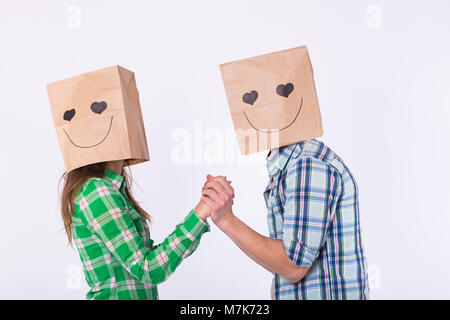 Amore giovane che coprono i loro volti con sacchetto di carta su sfondo bianco. Foto Stock