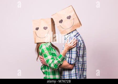 Amore giovane che coprono i loro volti con sacchetto di carta su sfondo bianco. Foto Stock