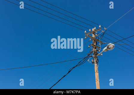 Telefono polo della lampada con fili elettrici contro il cielo blu Foto Stock