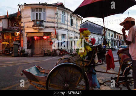 Driver Rikshaw e cinese tradizionale shop case su un tipico angolo di strada nel Patrimonio Mondiale UNESCO zona di Georgetown di Penang, Malaysia Foto Stock