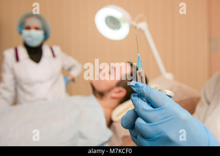 Close-up di mani in blu di guanti di gomma con la siringa. Preparazione per iniezione in chirurgia plastica clinica di bellezza. Foto Stock