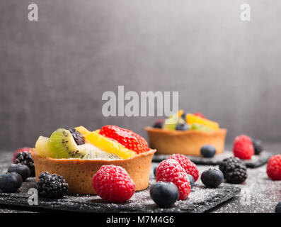 Appena fatti in casa torta di frutta sulla pietra nera compresse ricoperte con lo zucchero. Foto Stock