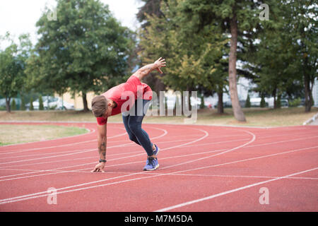 Sprinter uomo correre su piste rosse corsie in pista e sul campo Stadium di alta velocità vista superiore Foto Stock