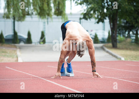 Sprinter uomo correre su piste rosse corsie in pista e sul campo Stadium di alta velocità vista superiore Foto Stock