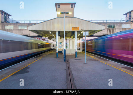 Stazione di Woking nel Surrey con treni storming passato le piattaforme sulla loro strada da e per Londra Foto Stock