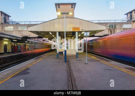 Stazione di Woking nel Surrey con treni storming passato le piattaforme sulla loro strada da e per Londra Foto Stock