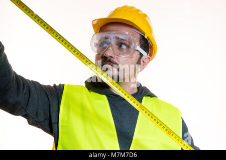 Le misurazioni con un metro, un uomo che vuole fare un lavoro senza la conoscenza, il lavoro senza esperienza. Fai da te, uomo vestito in giallo costruire Foto Stock