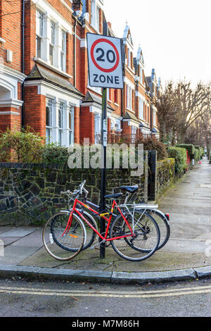 Due biciclette abbandonate incatenato ad un cartello stradale in una strada residenziale a nord di Londra, Regno Unito Foto Stock