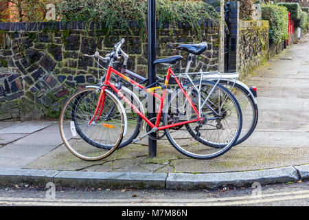 Due biciclette abbandonate incatenato ad un cartello stradale in una strada residenziale a nord di Londra, Regno Unito Foto Stock