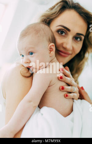 Bellissimo mamma orgogliosa trattiene il suo nuovo nato il figlio in una sala luminosa Foto Stock