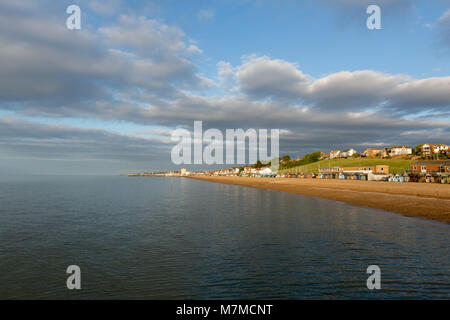 Vista da Hampton Pier a Herne Bay sulla costa della contea del Kent settentrionale durante la drammatica luce. Luce dorata che brilla sulla spiaggia di ciottoli e grandi nuvole bianche. Foto Stock