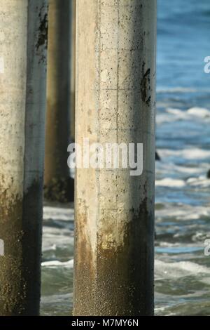 Onde si infrangono sul molo palificazioni Foto Stock