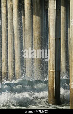 Onde si infrangono sul molo palificazioni Foto Stock