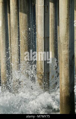 Onde si infrangono sul molo palificazioni Foto Stock