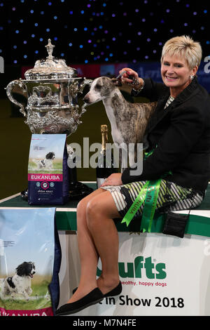 Stuzzicato il Whippet, con proprietario Yvette breve dopo che essa è stata nominata campionessa suprema durante il giorno finale di Crufts 2018 al NEC di Birmingham. Foto Stock