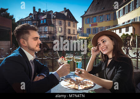 Due persone si siede insieme nella caffetteria locale con cibo e vino. Giovane donna con il mio ragazzo il pranzo in Alsazia. Moda giovane trattiene bicchieri di vino sulla terrazza Foto Stock