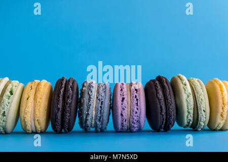 Amaretti colorati disposti ordinatamente su uno sfondo blu Foto Stock